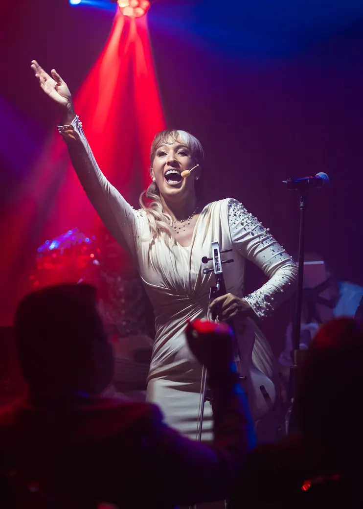 Tania on stage, arm raised, under red and blue lights